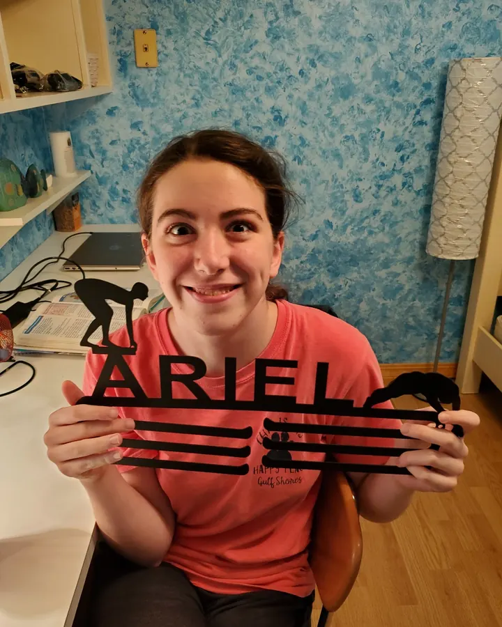 Ariel holding her swimming medal hanger