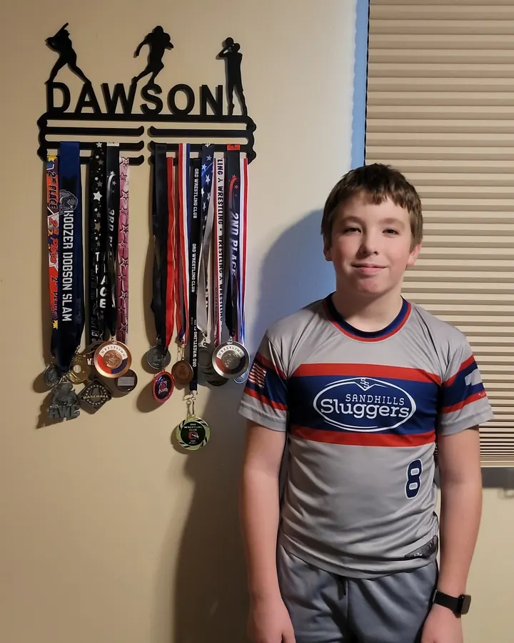 Dawson next to his medal hanger, full of wrestling and baseball medals