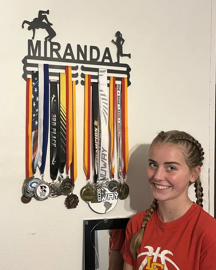 Miranda next to her personalized medal hanger and medals