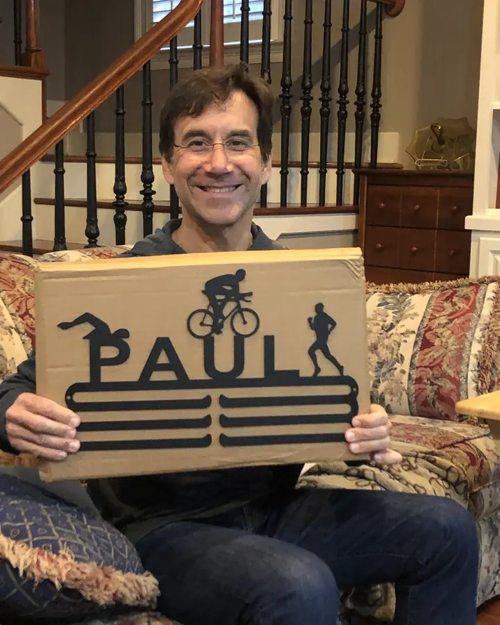 Paul holding his triathlon medal hanger
